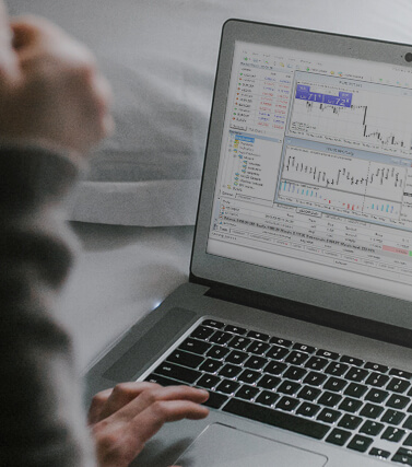 A laptop displaying the MetaTrader 4 windows.
